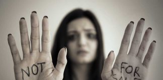 Handcuffed woman shows NOT FOR SALE on her palms