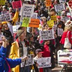Protesters holding signs about unions and saving the American dream