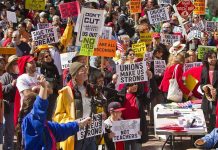 Protesters holding signs about unions and saving the American dream