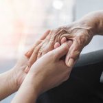 Young hands holding an elderly person's hand