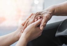 Young hands holding an elderly person's hand
