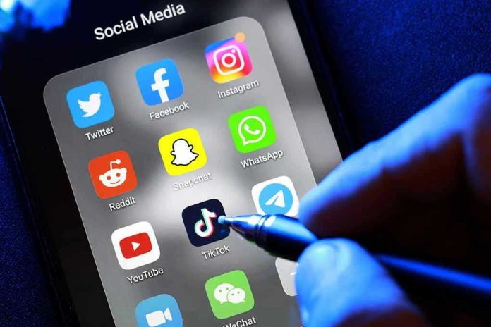 1907235274 Social media apps on phone screen with hand holding stylus