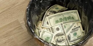 Trash bin filled with one hundred dollar bills