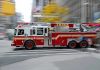 Red fire truck driving through city street crosswalk