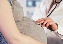 Doctor uses stethoscope on pregnant womans belly