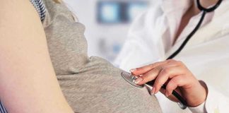 Doctor uses stethoscope on pregnant womans belly