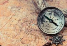 Old compass on a vintage map background