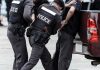 Police officers arresting a handcuffed person