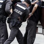 Police officers arresting a handcuffed person