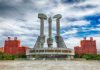 Concrete monument with hands holding tools under cloudy sky