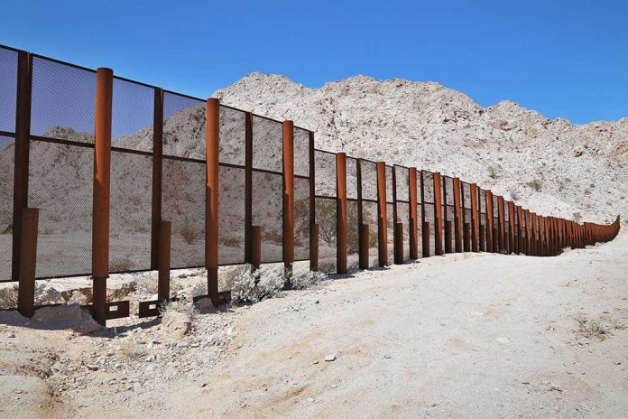 shutterstock_141374191.jpg A long border wall stretches across a desert landscape with mountains in the background