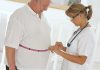 A healthcare professional measuring a patient's waist with a tape measure