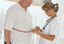 A healthcare professional measuring a patient's waist with a tape measure