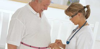 A healthcare professional measuring a patient's waist with a tape measure