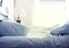 A cozy unmade bed with soft pillows and bedding in a well-lit room