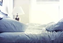 A cozy unmade bed with soft pillows and bedding in a well-lit room