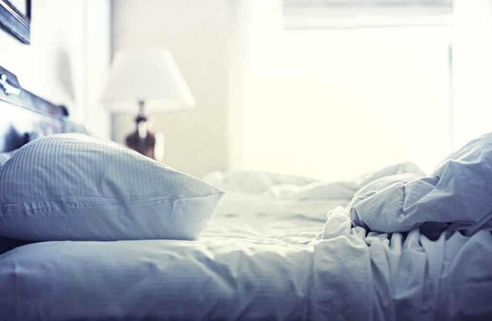 A cozy unmade bed with soft pillows and bedding in a well-lit room