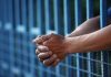 Close up of clasped hands resting on a blue fence