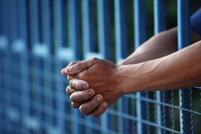 shutterstock_225023143.jpg Close up of clasped hands resting on a blue fence