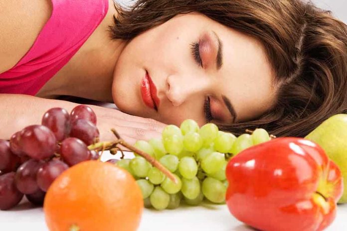 shutterstock_98819462.jpg A woman resting her head on a table surrounded by various fruits