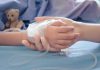 Childs hand with IV, held by adult.