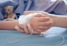 Childs hand with IV, held by adult.