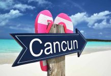 Cancun sign on a beach with flip-flops.