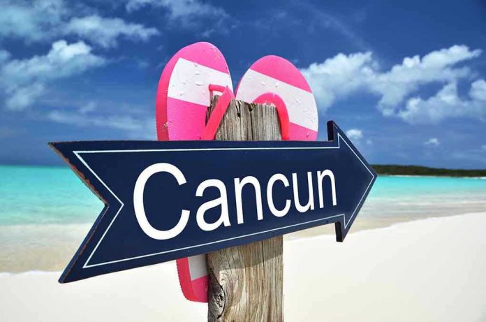 135553004 Cancun sign on a beach with flip-flops.