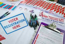 Voter registration table with forms, pens, and brochures.
