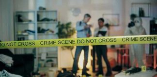 Crime scene with tape and investigators examining evidence.