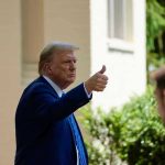 Man in suit giving thumbs up.