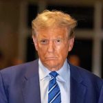 Man in blue suit and striped tie, serious expression.