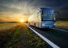 Bus driving on a road at sunset