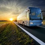 Bus driving on a road at sunset