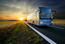 Bus driving on a road at sunset