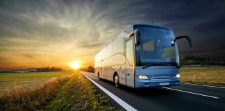Bus driving on a road at sunset