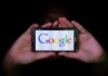 Hands holding smartphone displaying Google logo.