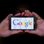 Hands holding smartphone displaying Google logo.