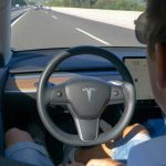 Man using autopilot mode in a Tesla car.