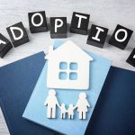 Adoption blocks, books, house, and family paper cutouts.