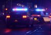 Police cars with flashing lights at a nighttime scene near a motel