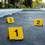 Rampage Leaves 3 Officers Dead Crime scene markers on asphalt with bullet casing.