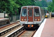 Metro train arriving at a station surrounded by greenery