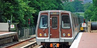 Metro train arriving at a station surrounded by greenery