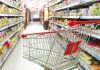 Empty shopping cart in grocery store aisle.