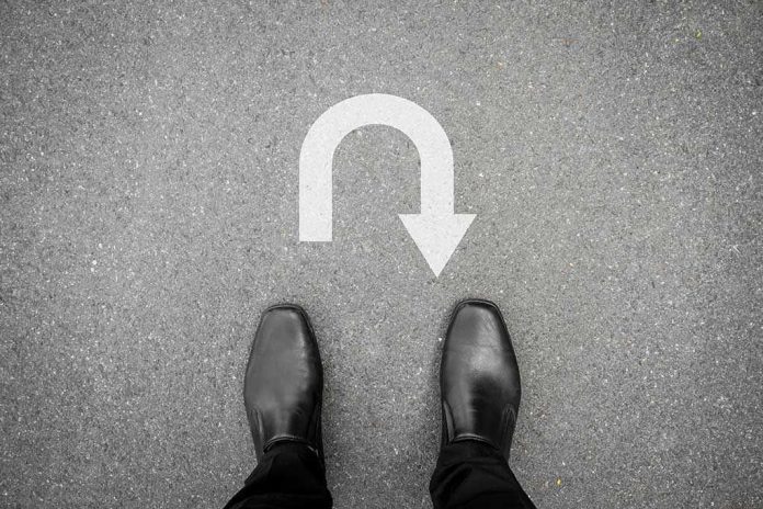 332468855 Feet in black shoes facing U-turn road marking.