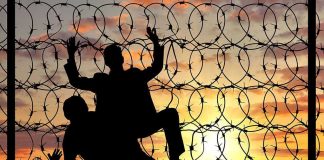 Corruption EXPLODED—How Did 20 Escape? Silhouettes of people climbing barbed wire fence.