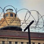 Murder Conviction Rocks NY Prison System Barbed wire in front of a prison tower.