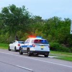Roadside Dangers Exposed — Officer Killed in Action Police car pulling over a white car