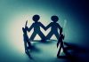 Paper cutout figures holding hands, creating a circle with shadows